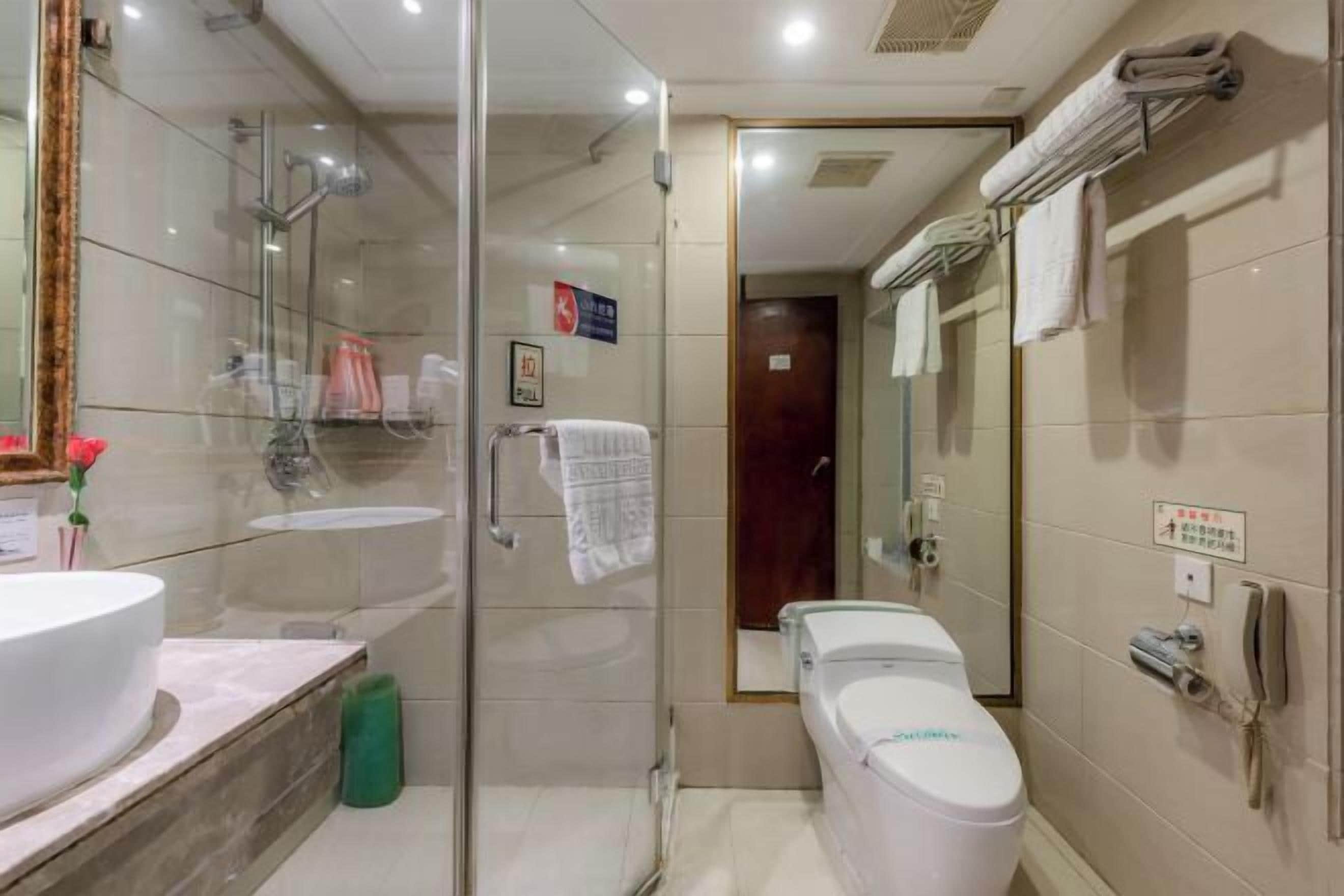 A modern bathroom with a glass shower enclosure, a toilet, and a sink.