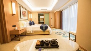 A hotel room with a bed, bedside table, a round table with tea set, and a window with curtains. - Mei YI Hotel (Yiliang)