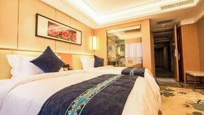 A hotel room with a large bed, a bedside table, a mirror, and a door leading to another room.