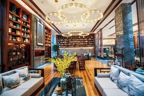 A spacious lobby with a wooden floor, a central seating area with sofas, a large bookshelf, and a decorative chandelier. - Mei YI Hotel (Yiliang)