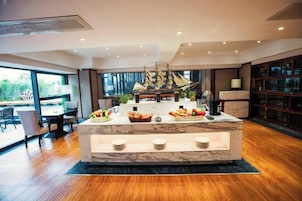 Cozinha moderna com ilha de mármore, um modelo de navio e uma estante de livros.