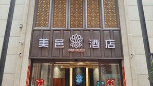 A hotel with a traditional design, featuring a prominent logo and decorative panels above the entrance. - Mei YI Hotel (Yiliang)