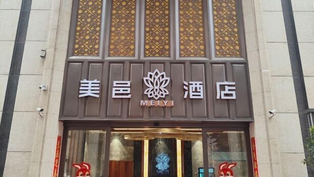 A hotel with a traditional design, featuring a prominent logo and decorative panels above the entrance.