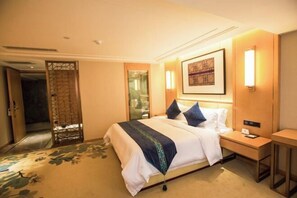 Una habitación de hotel con cama, mesita de noche y lámpara de pared.