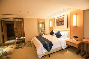 Una habitación de hotel con cama, mesita de noche y un cuadro en la pared.