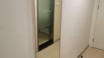 Um corredor estreito com uma porta de vidro que dá para um banheiro.