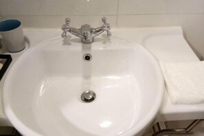 A white bathroom sink with a chrome faucet and a towel on the right side.