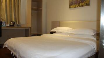 A neatly made bed with white linens in a hotel room.