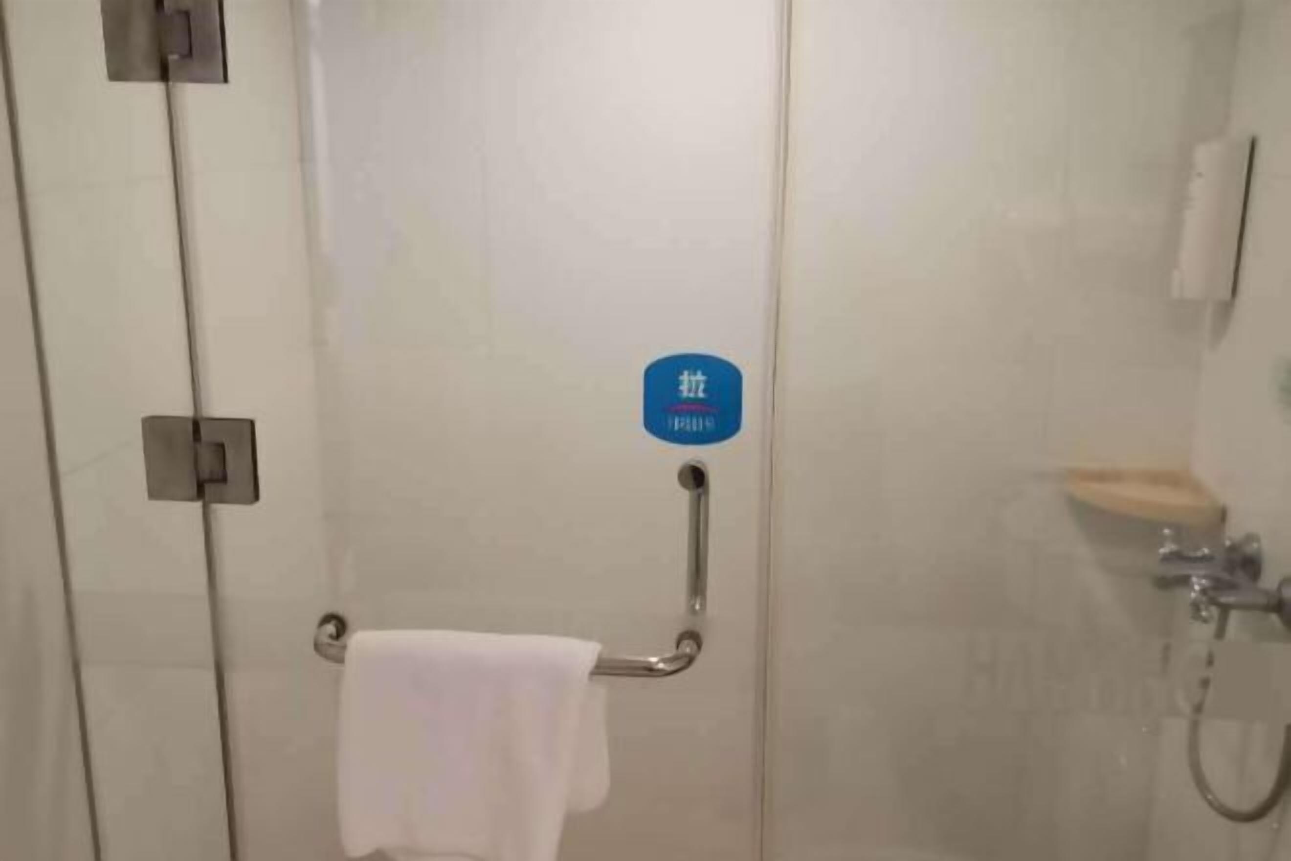 A bathroom with a towel rack, a shower area, and a blue sign with text.