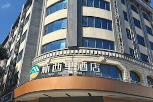 Edifício de hotel com fachada curva, várias janelas e uma placa de destaque com texto em chinês e inglês.