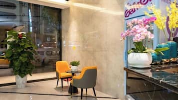 Un hall de hotel con zona de estar, un ventanal grande y una exhibición de flores.