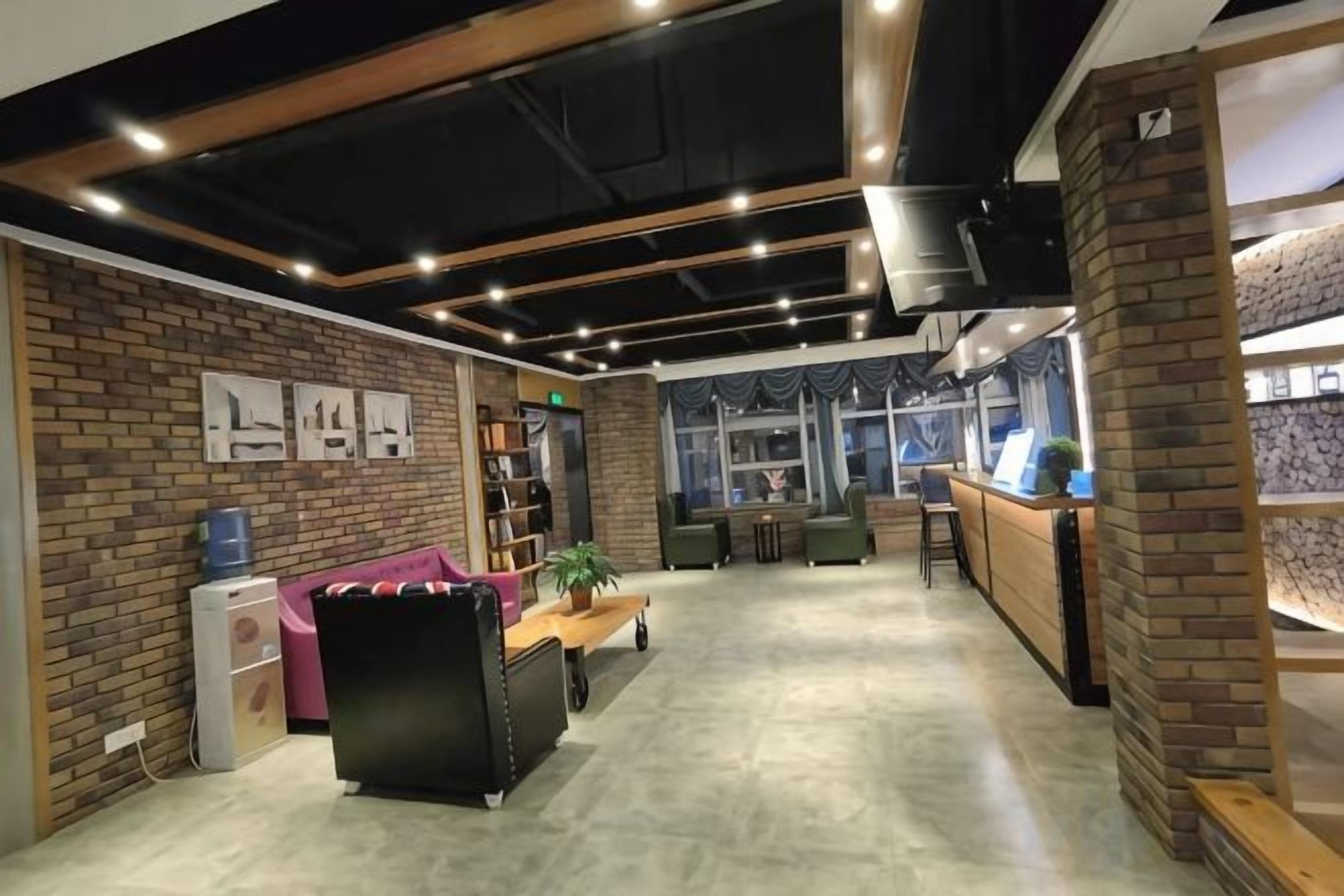 A modern interior with a brick wall, a reception desk, and a seating area with a sofa and chairs.