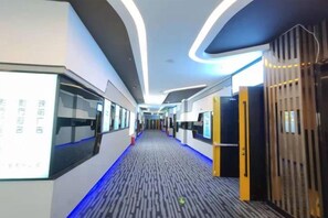 A modern hotel corridor with a patterned carpet, curved ceiling lights, and a wooden wall with vertical slats. - Renshou Wanye Sunshine Hotel (Renshou)