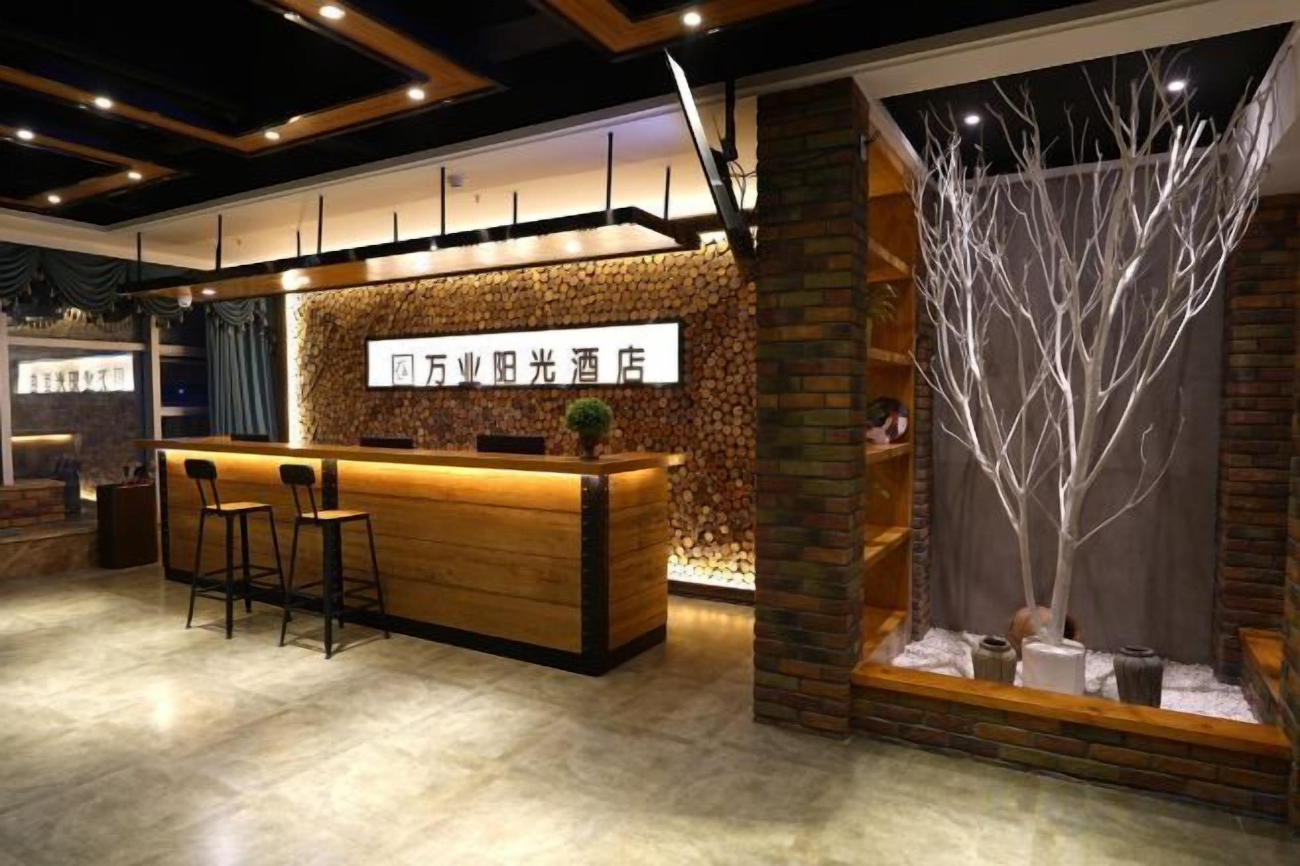 Una zona de recepción con mostrador de madera, taburetes de bar y una planta decorativa.