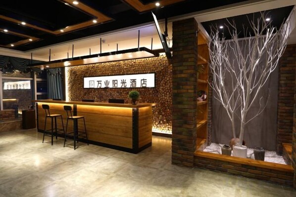 A reception area with a wooden counter, bar stools, and a decorative tree.