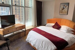 A hotel room with a bed, a desk with a TV, a window with curtains, and a painting on the wall. - Renshou Wanye Sunshine Hotel (Renshou)