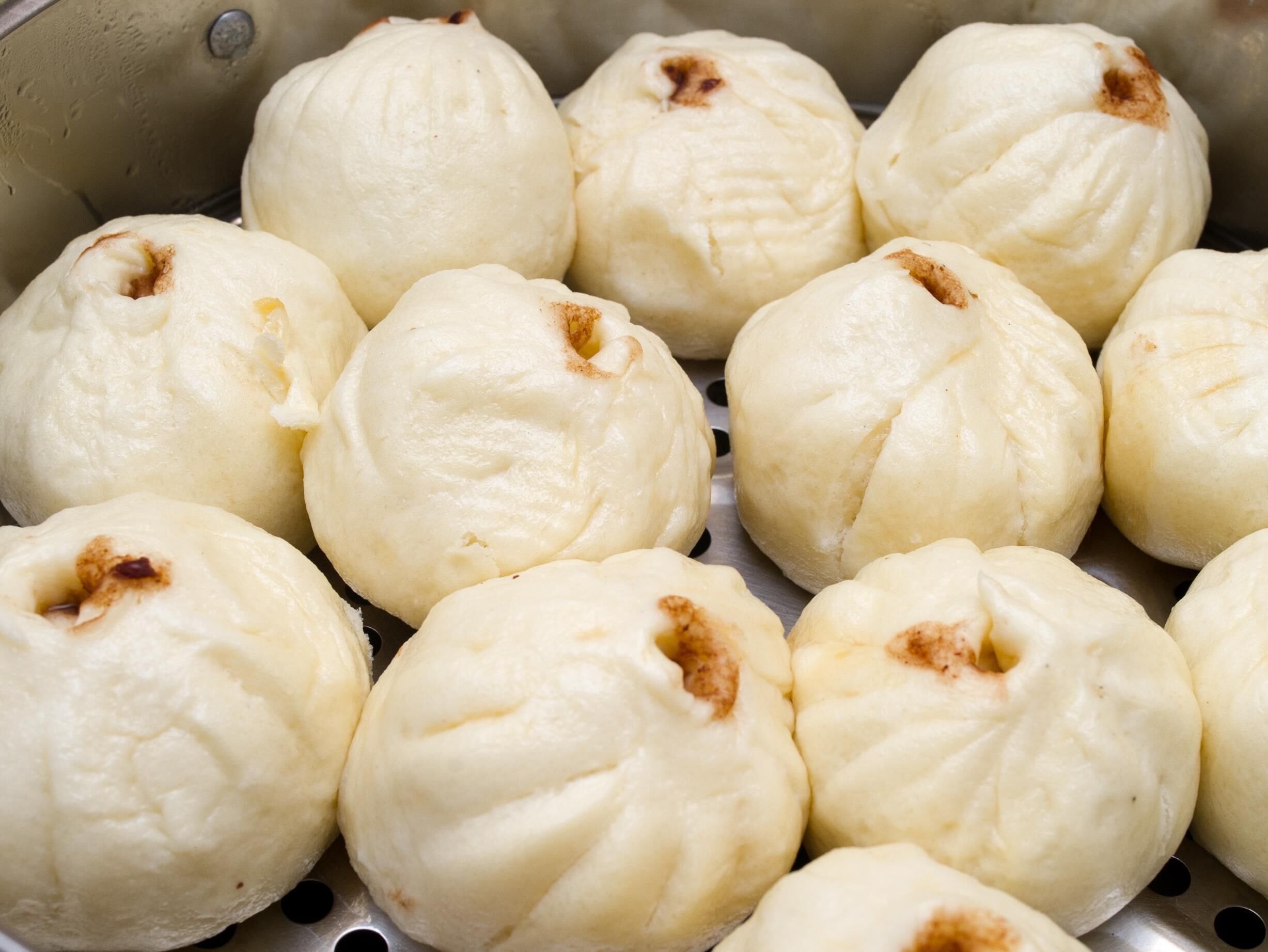 A steamer with several white, round, steamed buns.