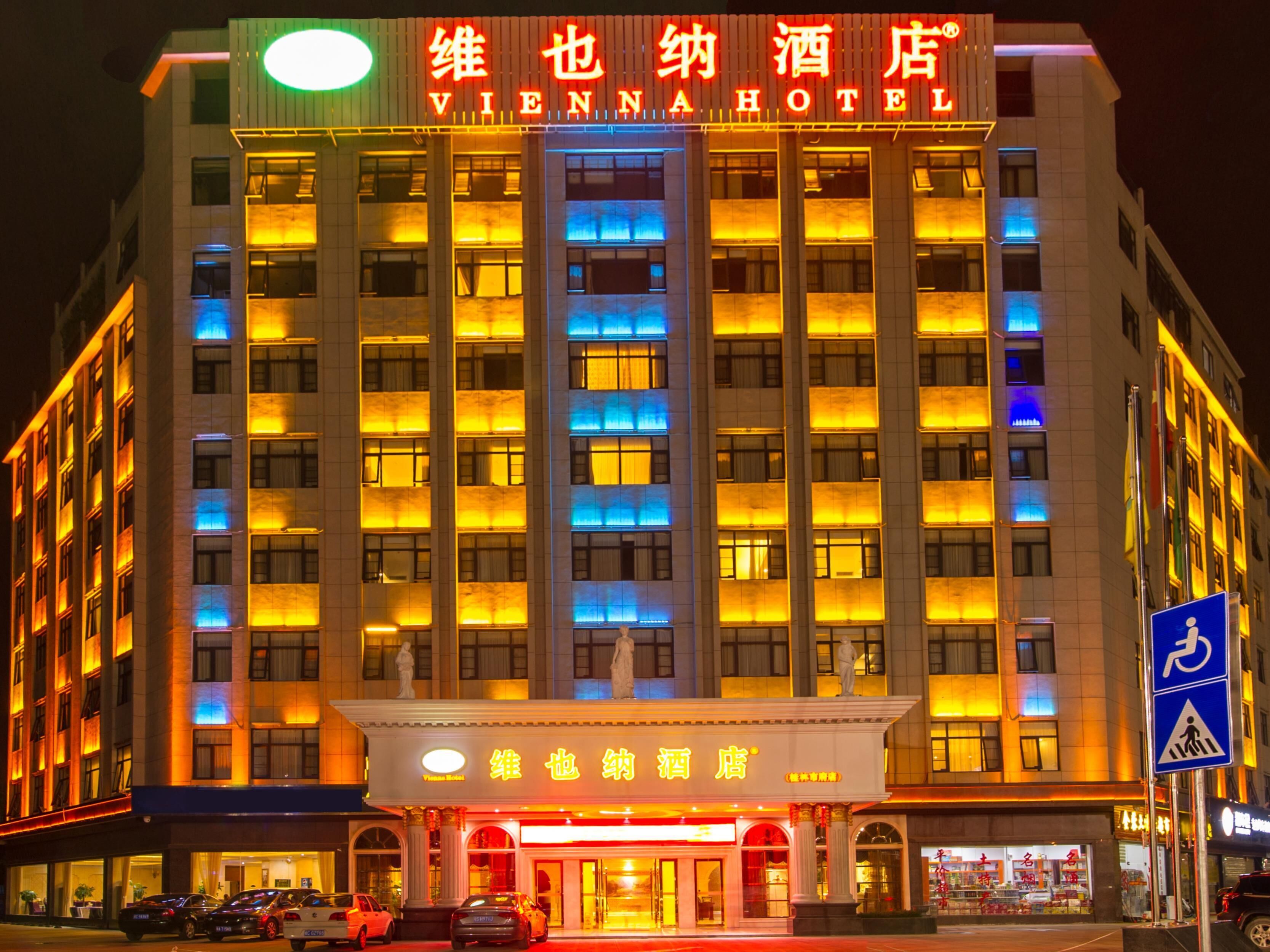 Un hotel a più piani con insegne illuminate, un ingresso ben visibile e un segnale di attraversamento pedonale.