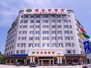 Un hotel de varios pisos con un letrero llamativo en la parte superior, numerosas ventanas y una bandera en el lado derecho.