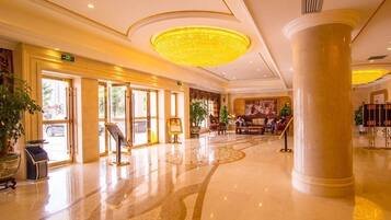 A spacious lobby with a large chandelier, a reception desk, and a seating area.
