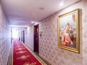 A hotel corridor with patterned wallpaper, a red carpet, and a framed painting on the wall. - Vienna Hotel (Wanda Store of Guilin Municipal Government) (Guilin)