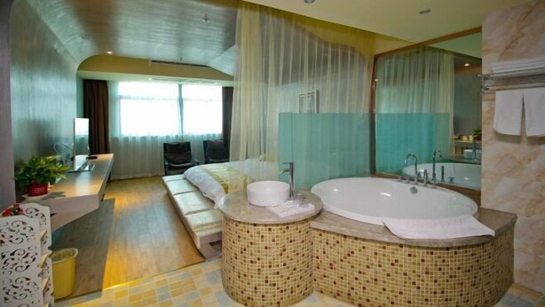 Ein modernes Badezimmer mit einer großen Badewanne, einem separaten Waschbeckenbereich und einer Sitzecke mit einer Bank.