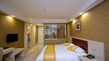 A hotel room with a bed, bedside table, and a TV mounted on the wall.