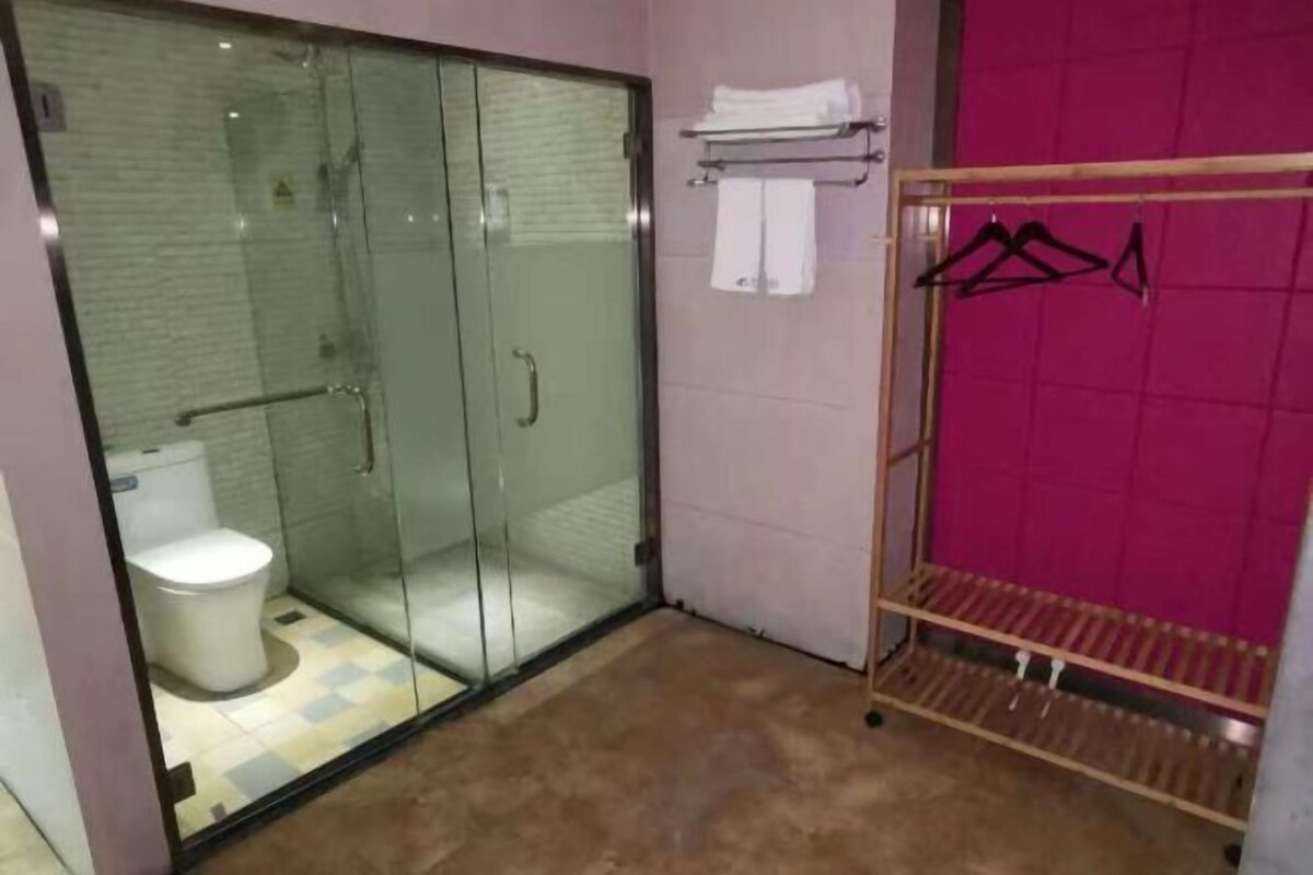 Une salle de bain avec une douche à parois de verre, des toilettes, un porte-serviettes avec des serviettes et un porte-vêtements.