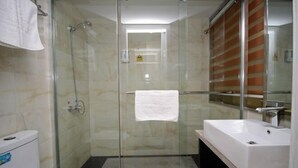 Ein modernes Badezimmer mit einer gläsernen Dusche, einem weißen Waschbecken und einer Toilette.