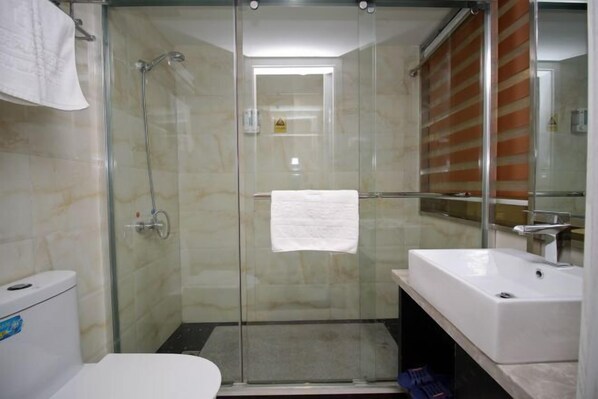 Une salle de bain moderne avec une douche à parois de verre, un lavabo blanc et des toilettes.