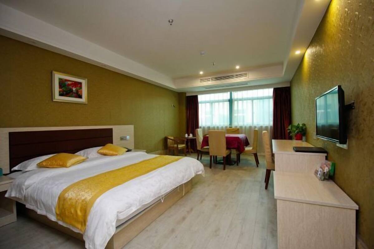 A hotel room with a bed, a desk, and a TV.