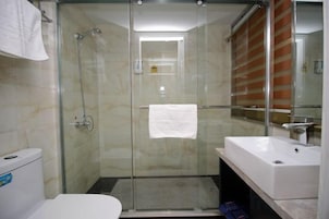 A bathroom with a glass shower enclosure, a white sink, and a toilet.