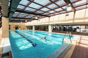 An indoor swimming pool with clear water, a diving board, and a tiled floor. - Sea Party Hotel (Laixi)