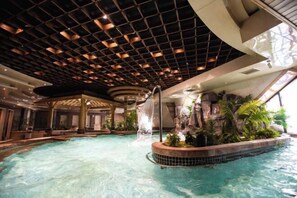 Ein Innenpool mit Wasserfall, umgeben von tropischen Pflanzen und einem modernen Deckenstil.