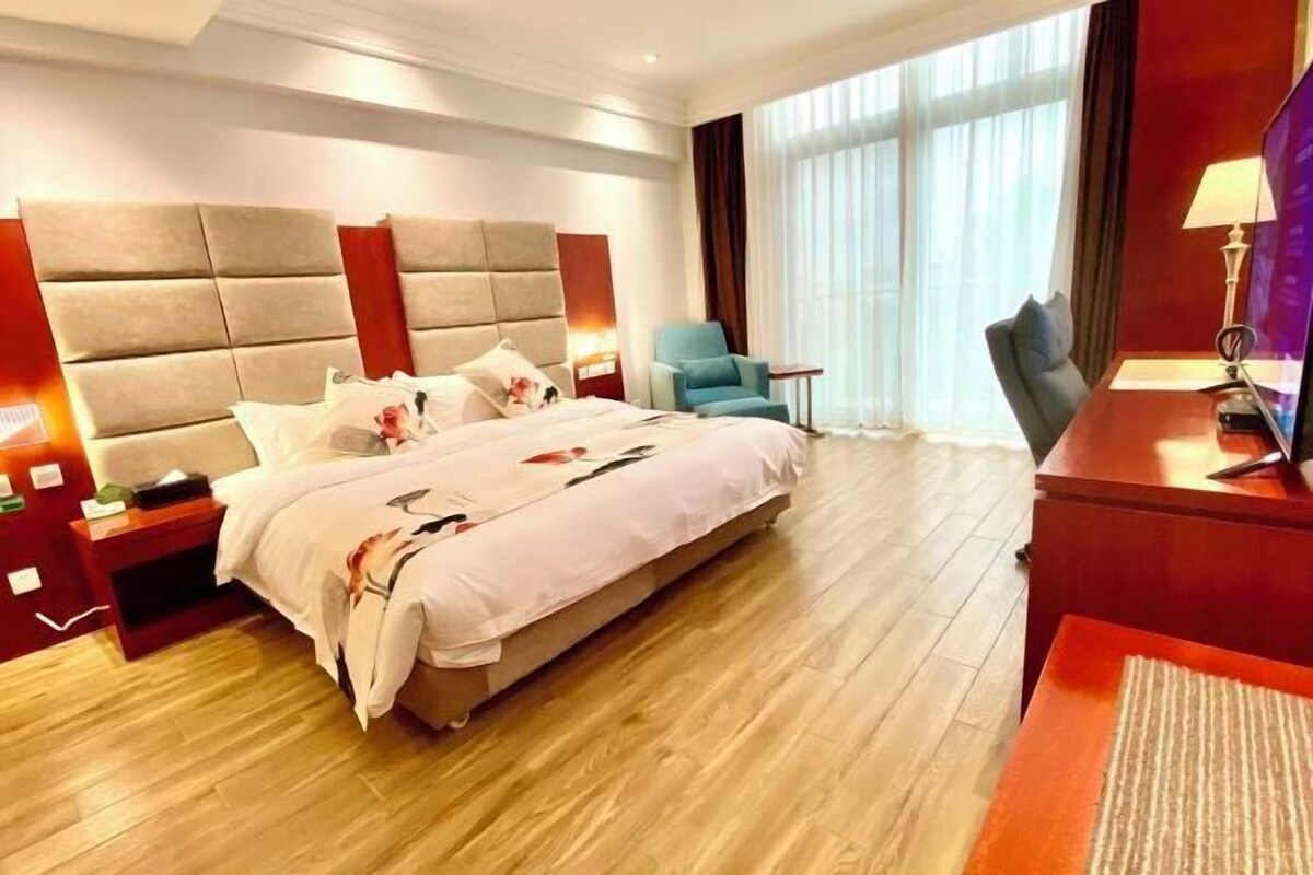 Un cuarto de hotel con una cama grande, mesitas de noche, un escritorio y una silla.