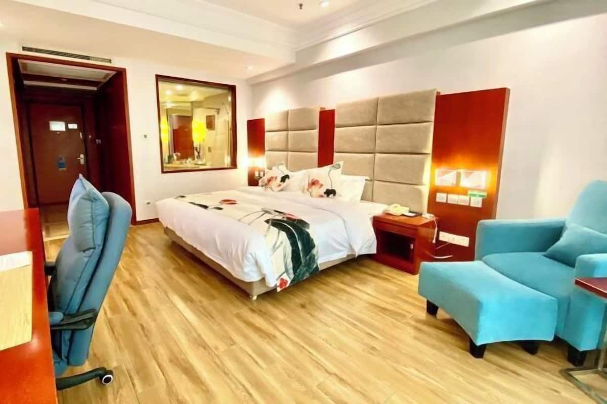 A hotel room with a large bed, a desk, a chair, and a mirror.