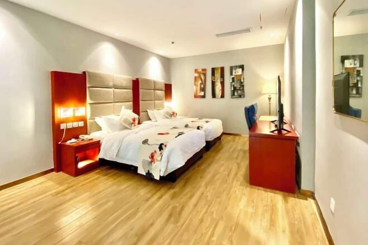 A hotel room with a large bed, bedside tables, a desk, and a mirror.
