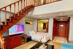 Habitación de hotel con una escalera de madera, una cama, un televisor y un espejo.