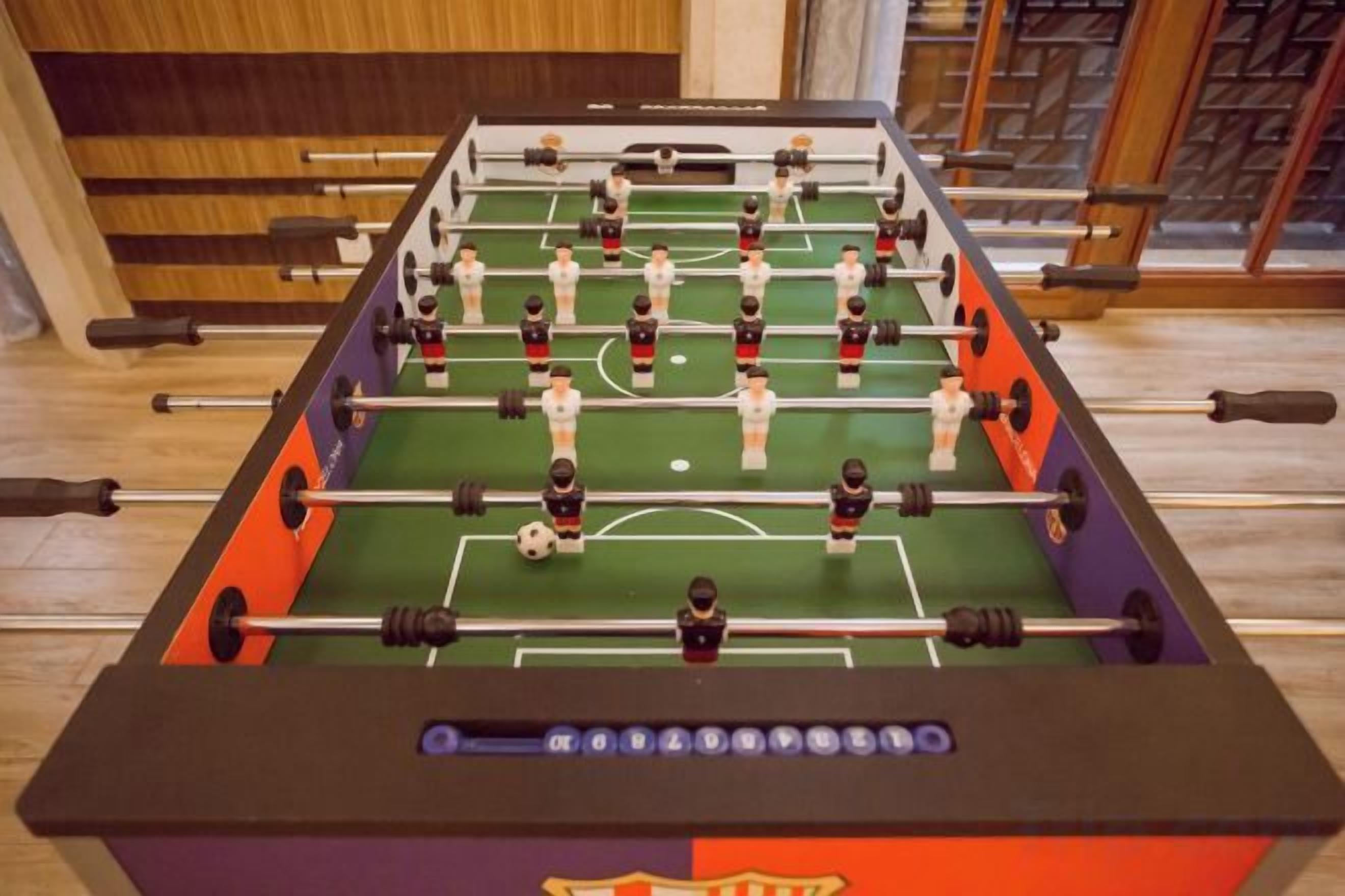 Een tafelvoetbaltafel met een voetbalveld-indeling, inclusief doelpalen en speelfiguurtjes.