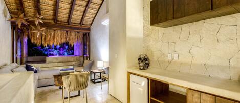 A modern interior with a thatched ceiling, a stone wall, and a minimalist design.