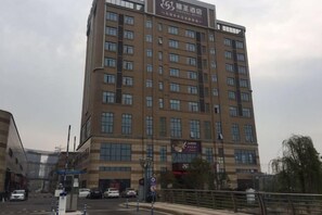 A multi-story building with a flat facade, numerous windows, and a sign at the top. - Yasheng Hotel (Taicang Port Area) (Taicang)