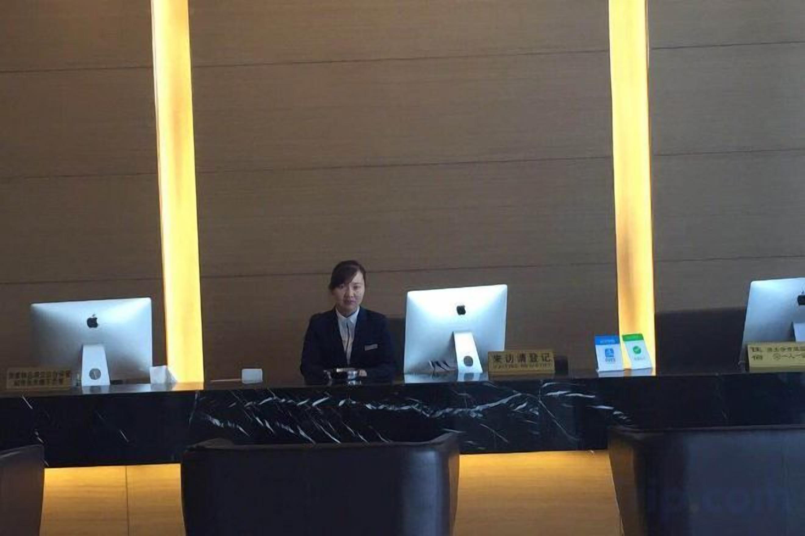 A reception desk with two Apple iMac computers, a nameplate, and a black tablecloth.