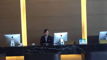 A reception desk with two Apple iMac computers, a nameplate, and a black tablecloth.