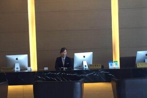 Una mesa de recepción con dos computadoras Apple iMac, una placa con nombre y un mantel negro.