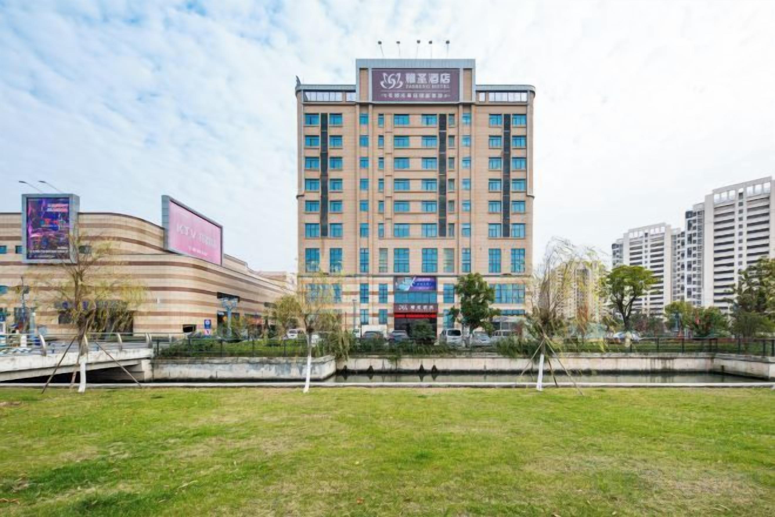 A multi-story hotel with a flat facade, a central entrance, and a surrounding grassy area.