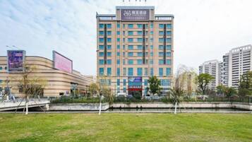 A multi-story hotel with a flat facade, a central entrance, and a surrounding grassy area.