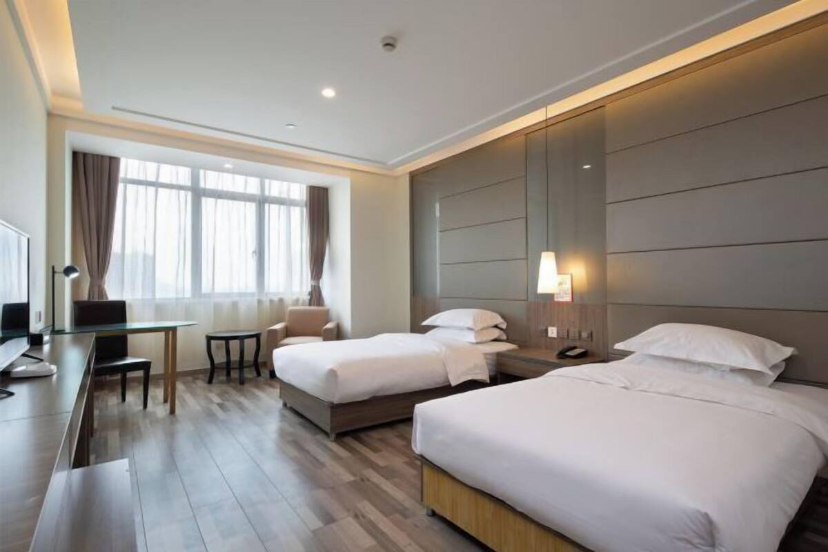A hotel room with two beds, a desk, and a chair.