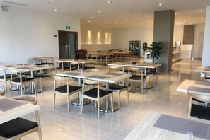 A spacious dining area with multiple tables and chairs, a clean floor, and a modern interior design. - Yasheng Hotel (Taicang Port Area) (Taicang)