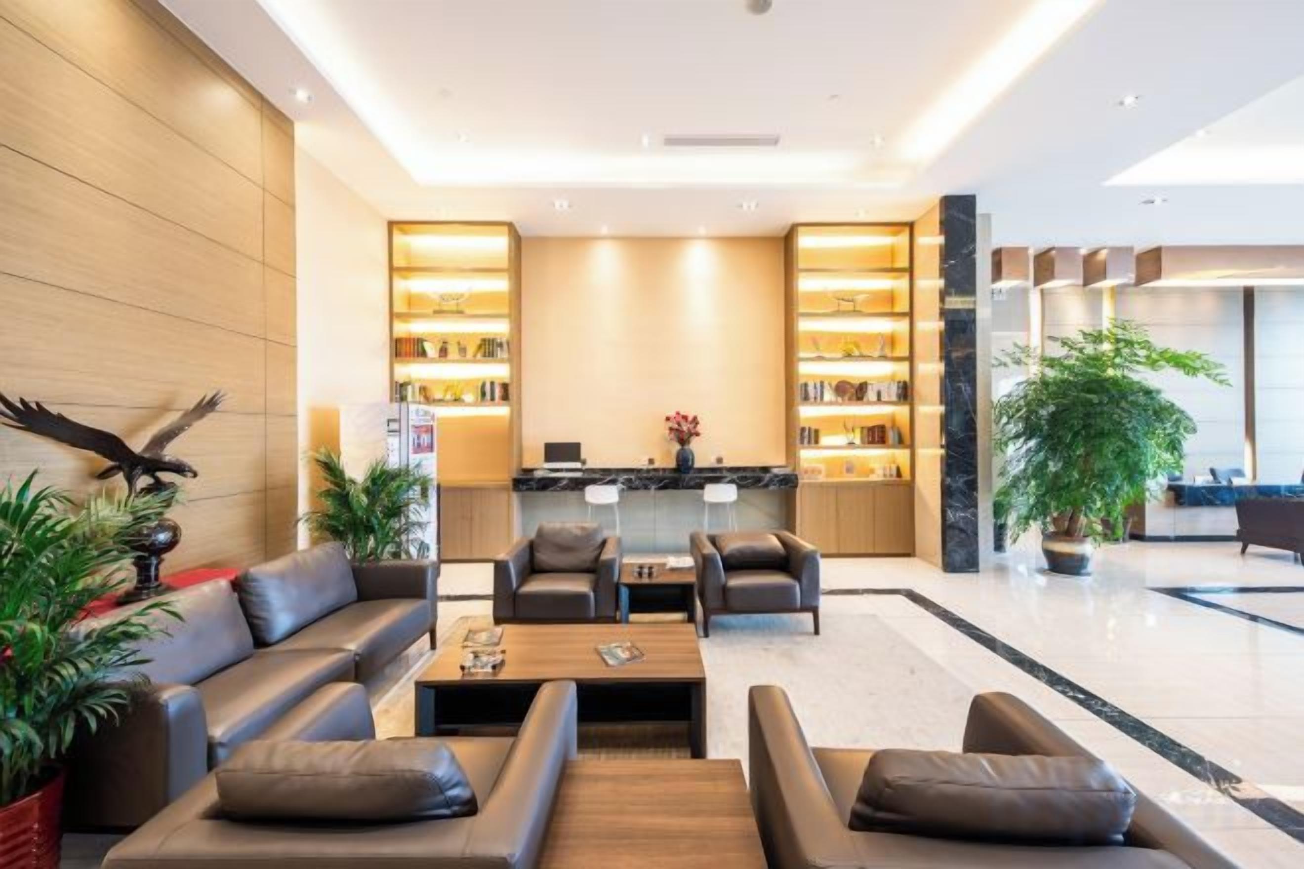 A modern lobby with a reception desk, seating area, and a large plant.