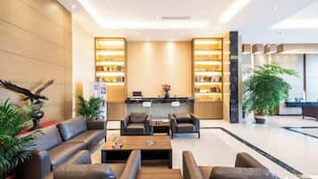 A modern lobby with a reception desk, seating area, and a large plant.